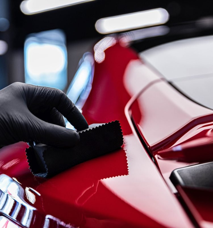 Application of ceramic coating in car detailing studio or car wash. Beautiful red car paint.