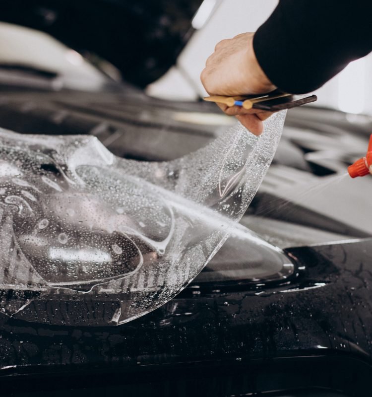 Male worker wrapping car with ptotective foil